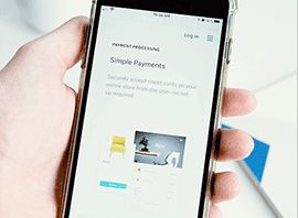 Hand holding a smartphone displaying an online payment processing page.